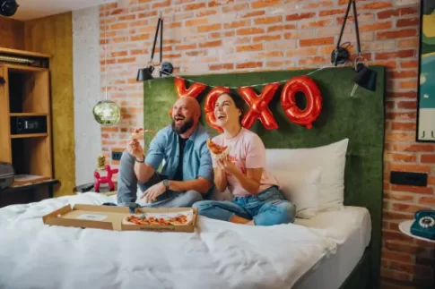 couples eating pizza and laughing in hotel one66 room
